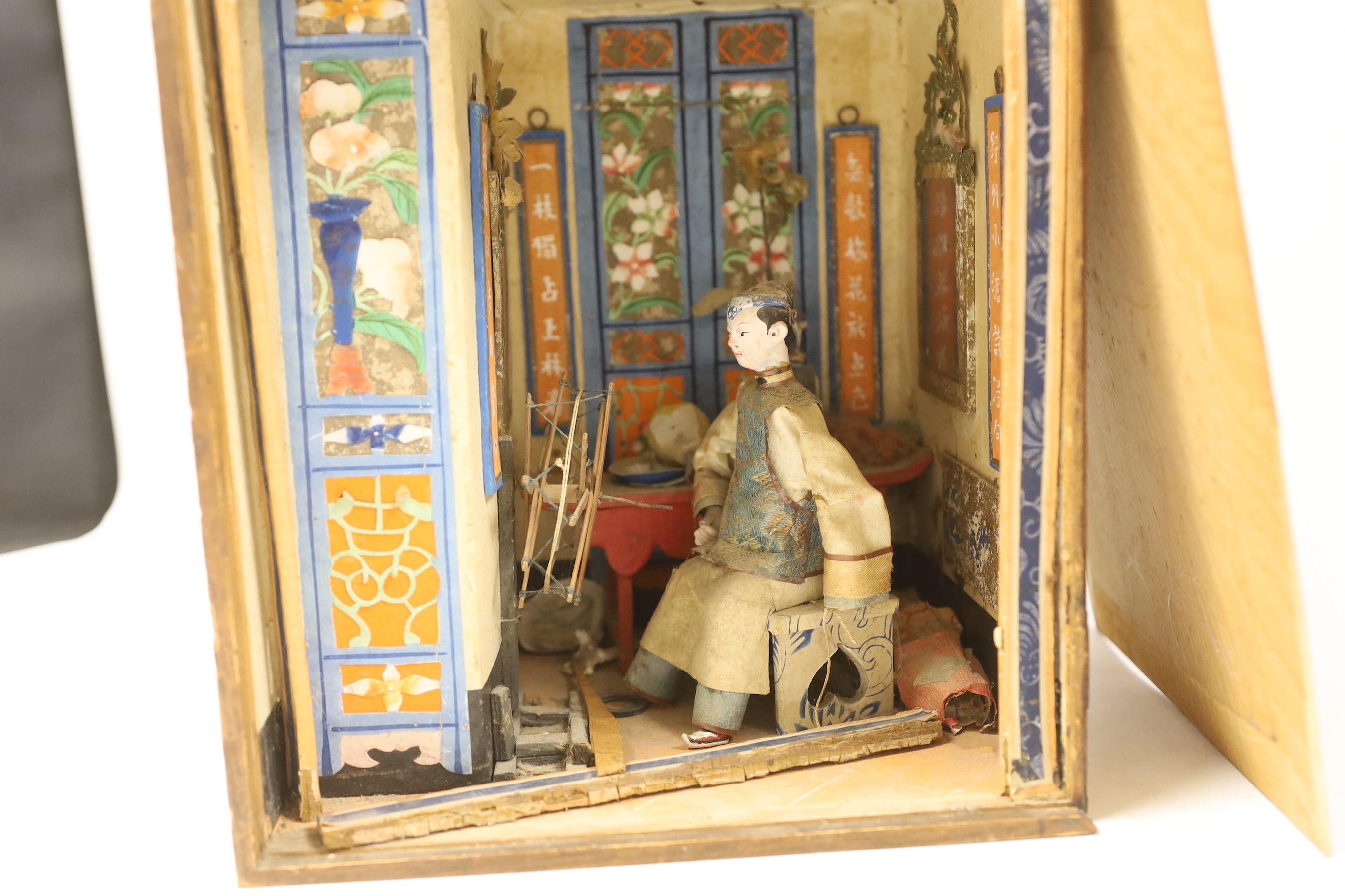 A Chinese card, paper and silk diorama depicting a seated artisan at a spinning wheel, 19th century, (label to the side of box) 22cm wide x 24.5 cm high
